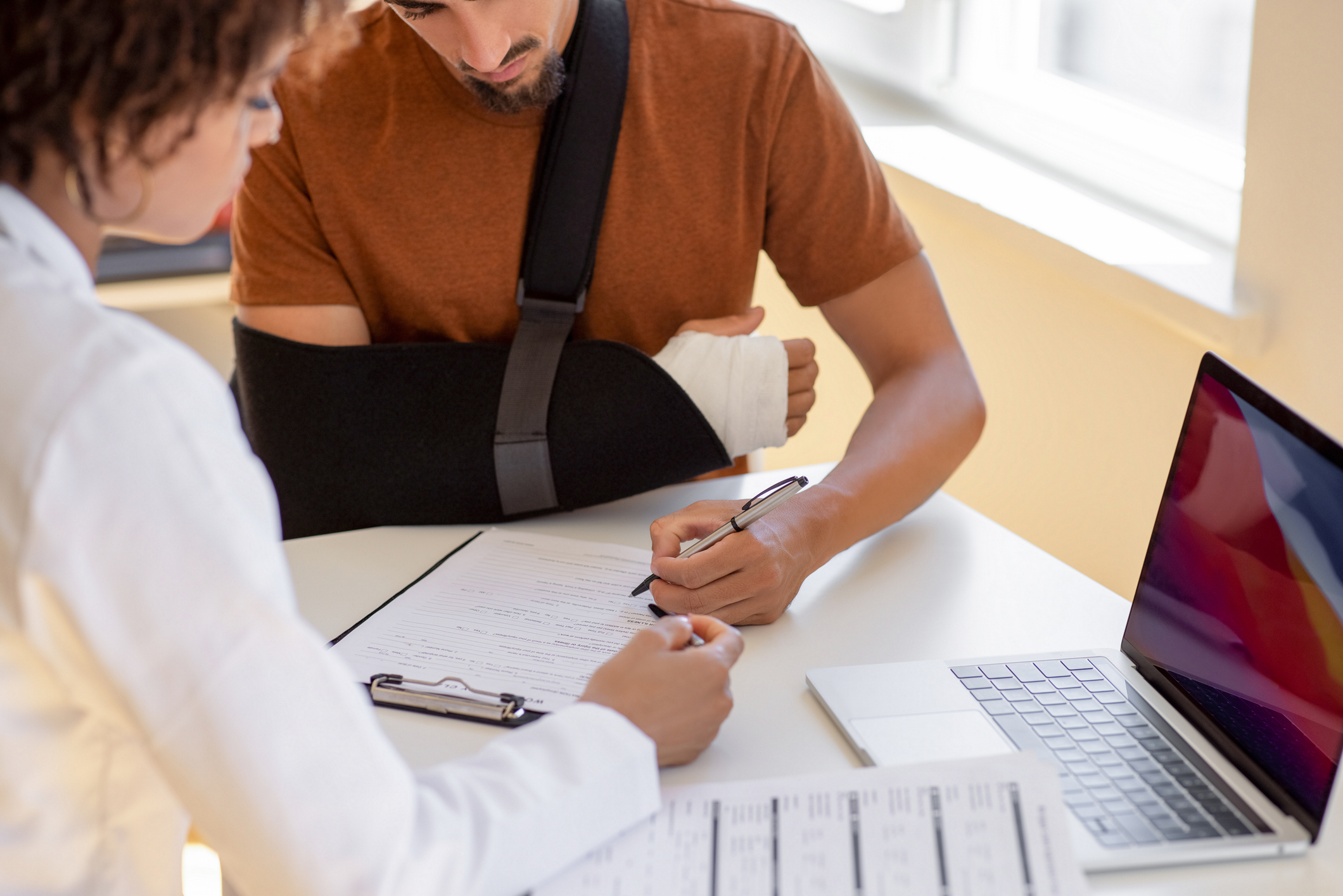 Doctor and patient sit and talk. Filling medical insurance form