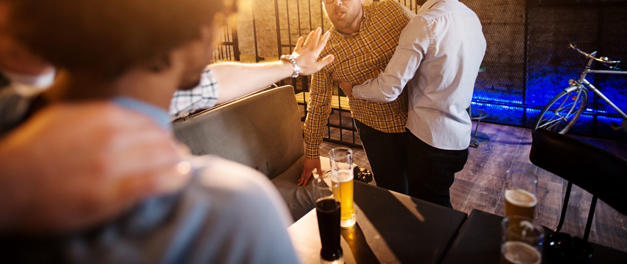 Friends preventing fighting and trouble of two mad guys in the bar